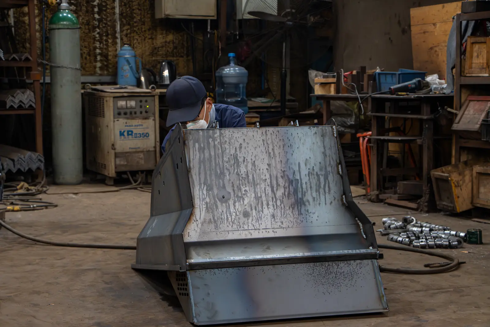 Bare manganese-steel loader bucket on the workshop floor before painting