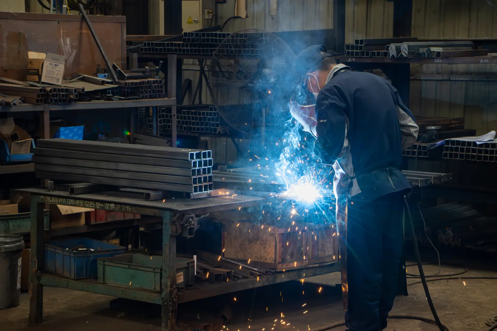 Welder at work on a loader frame at the BOB-LIFT factory in Xuzhou, sparks flying from the torch