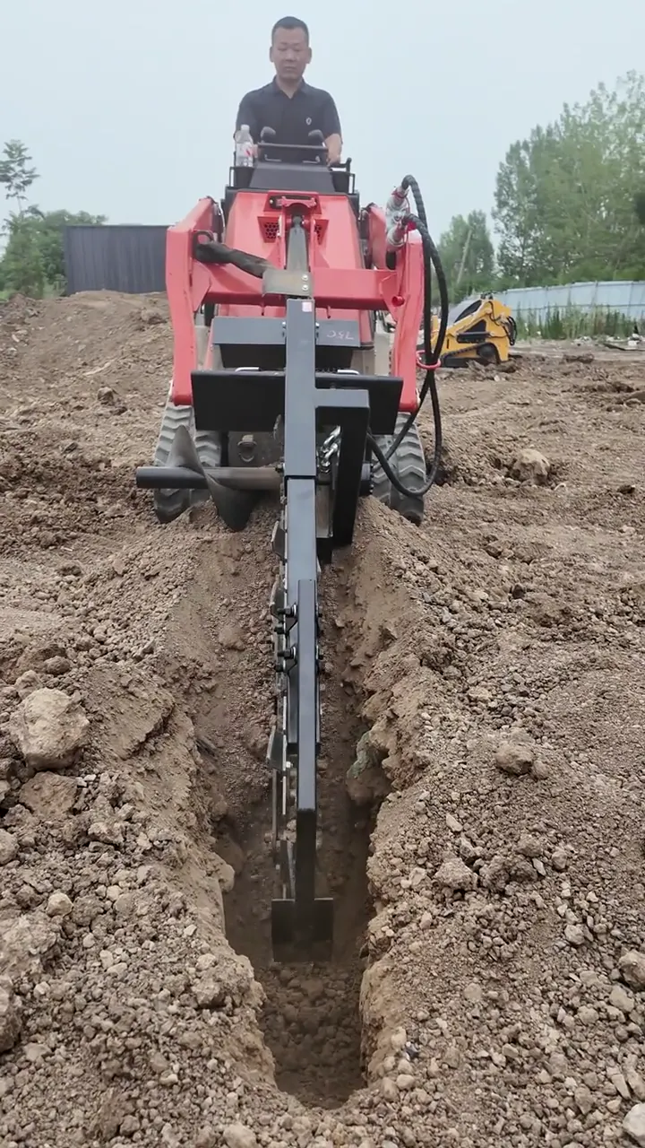 Operator standing on a red BL-T1000-H tracked mini skid steer, cutting a narrow trench in stony soil with a chain trencher attachment